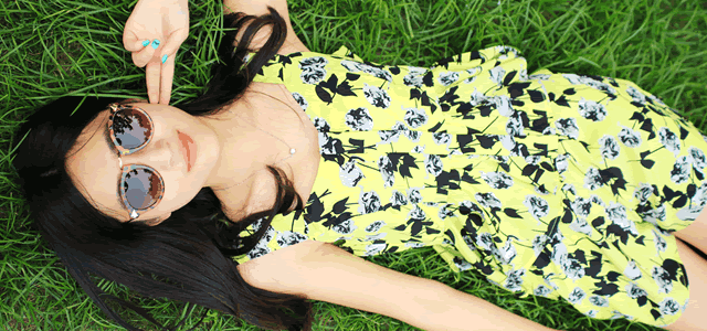 笑顔で芝生に寝転ぶサングラスをかけた女性